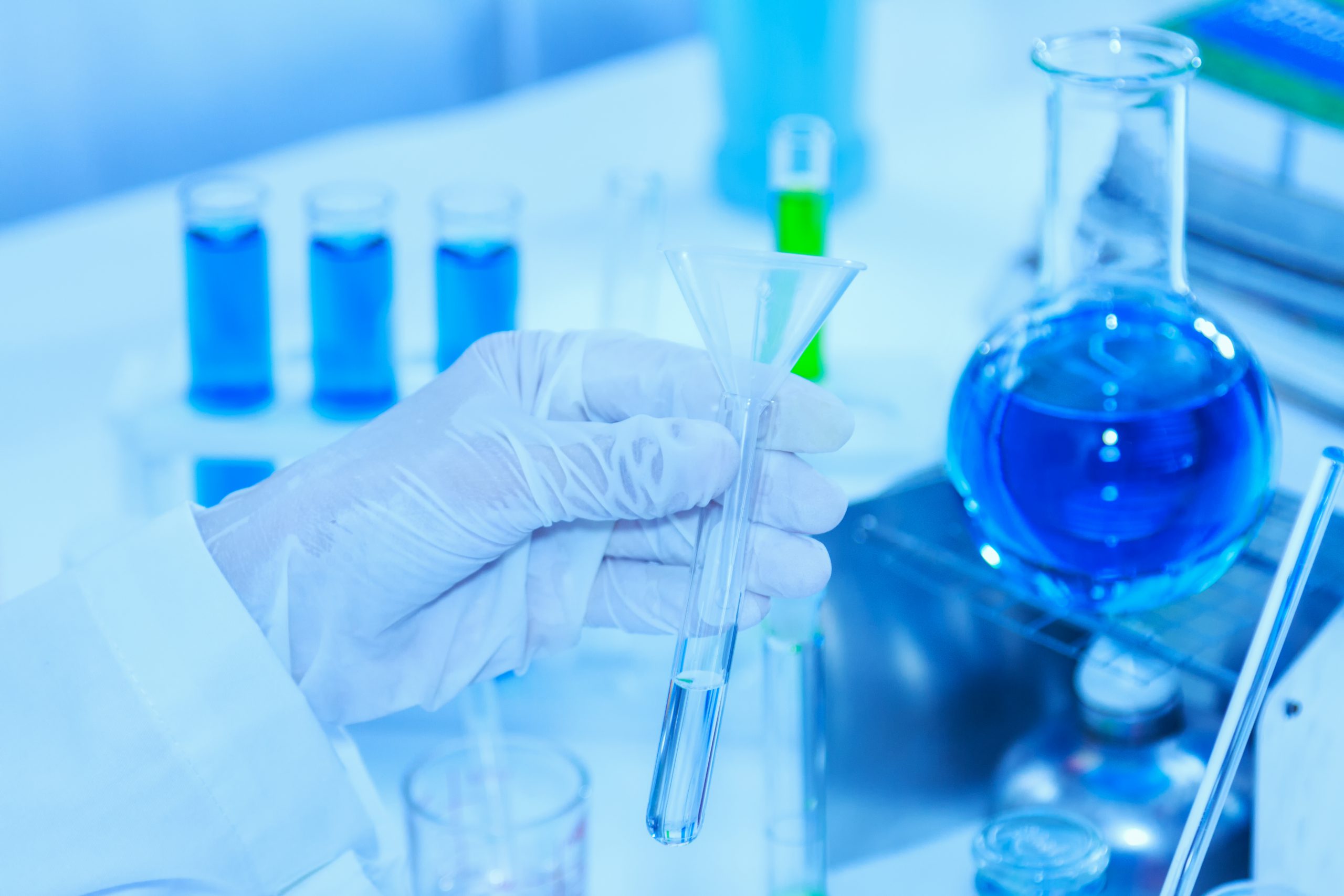 Flask in scientist hand with test tubes for analysis.